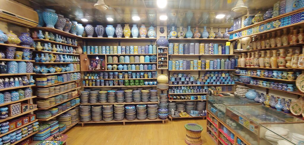 Shelves filled with blue, white and multicoloured Jaipur blue pottery