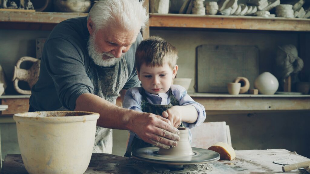 Hands centring wet clay on a pottery wheel during a beginner class