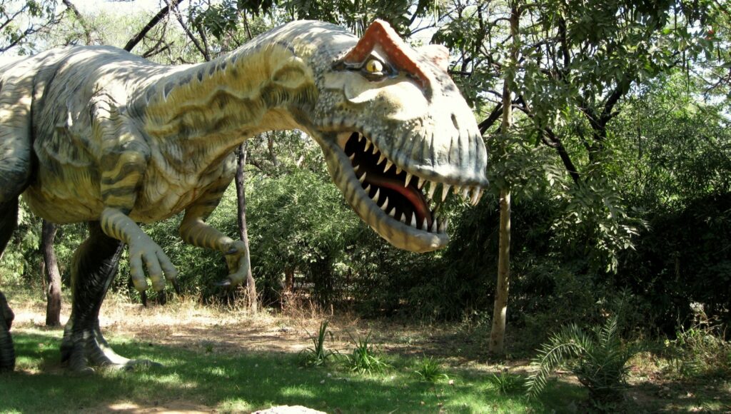 A dinosaur model among trees at Indroda Dinosaur and Fossil Park in Gandhinagar.